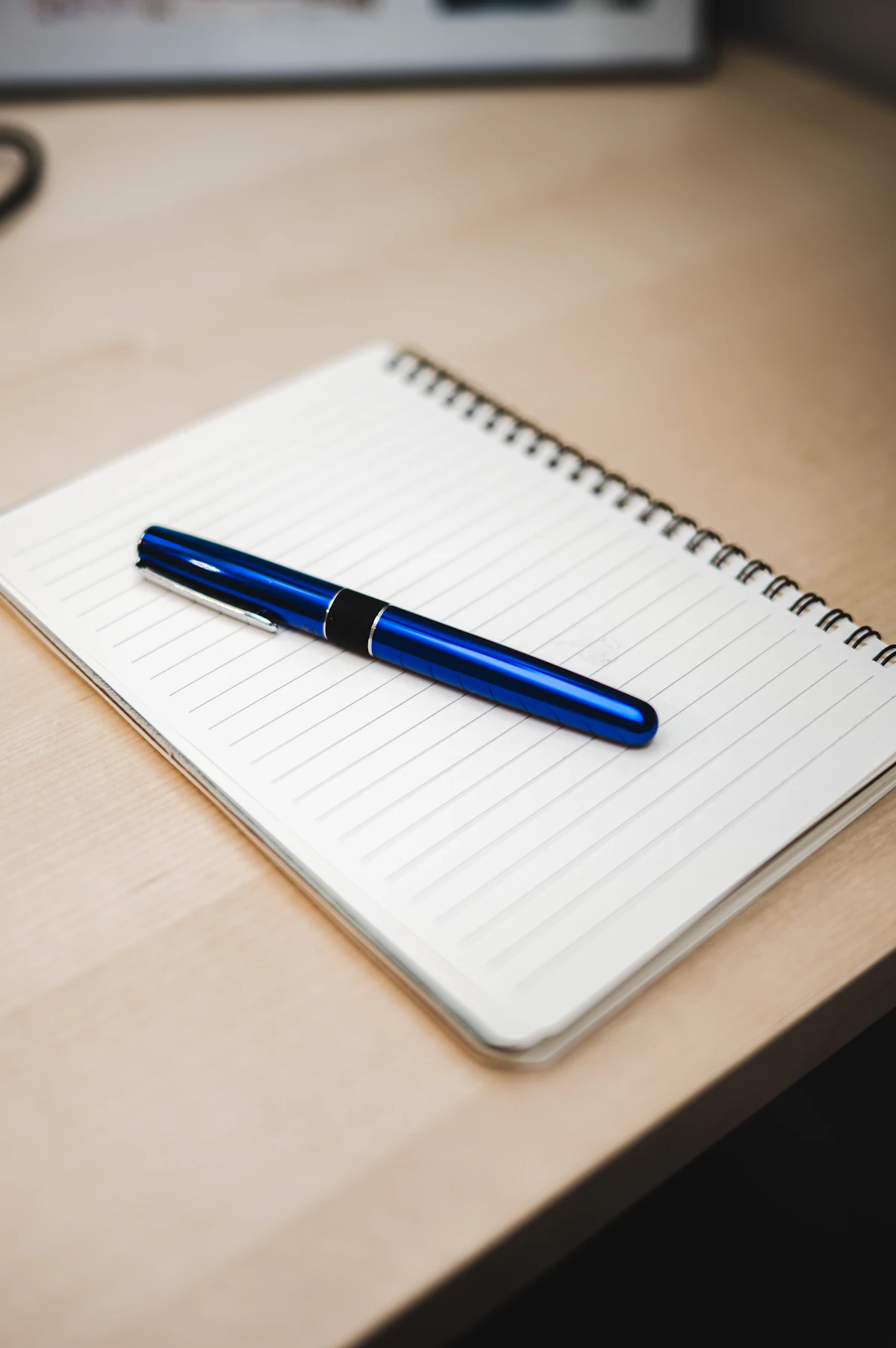 A fountain pen resting on an open notebook on a wooden desk, evoking the heritage craftsmanship associated with Montblanc and other legacy luxury brands.