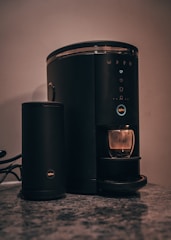 A compact coffee maker steaming fresh brew on a bright kitchen counter.
