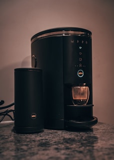 Close-up of a sleek coffee maker on a rustic kitchen countertop.