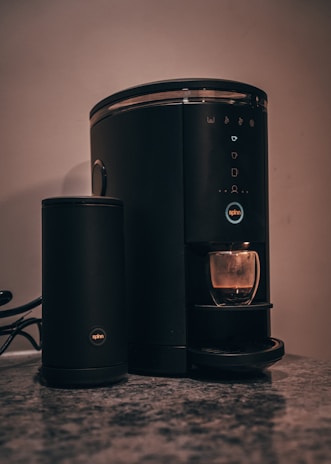 Close-up of a sleek coffee maker on a rustic kitchen countertop.