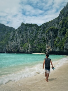 a man walking along a beach next to the ocean
