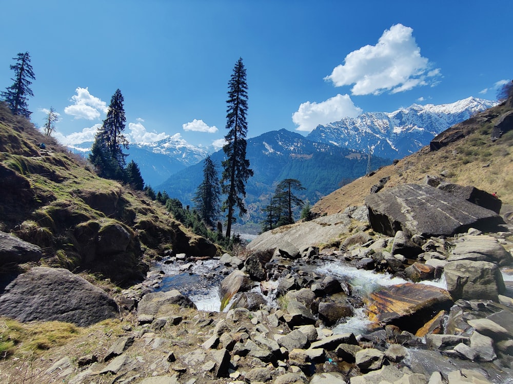 a stream running through a rocky valley surrounded by mountains