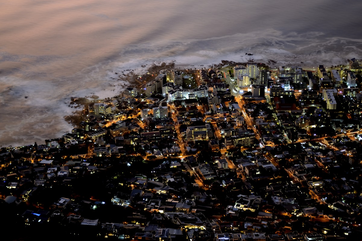 Aerial view of a city at night, civic-scale / community-erosion register