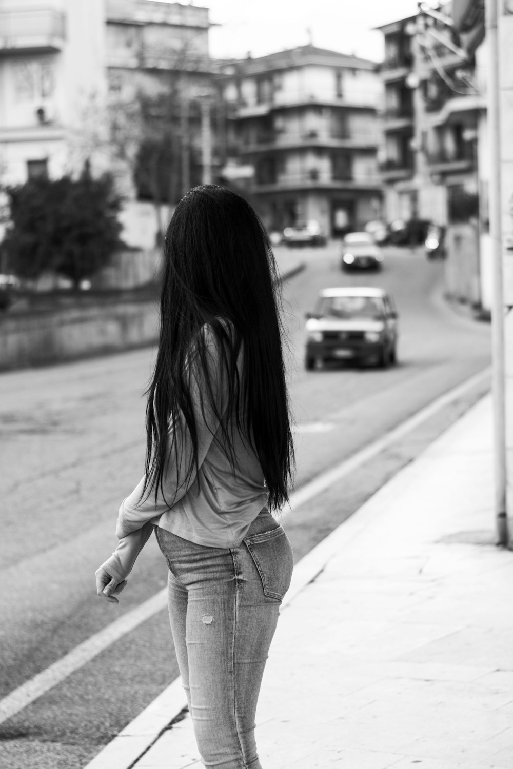 a woman walking down a sidewalk next to a street