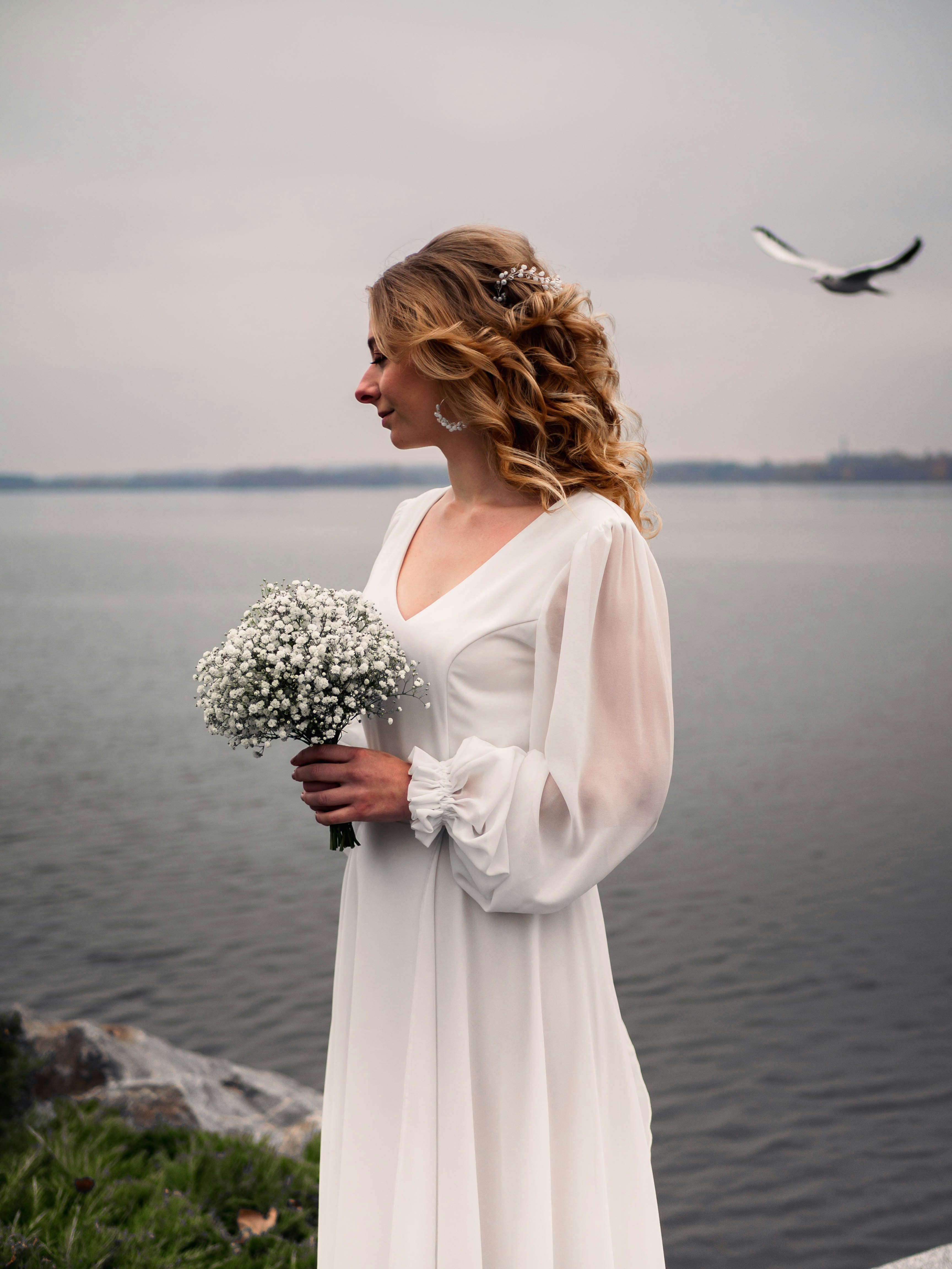 a woman in a white dress holding a bouquet of flowers