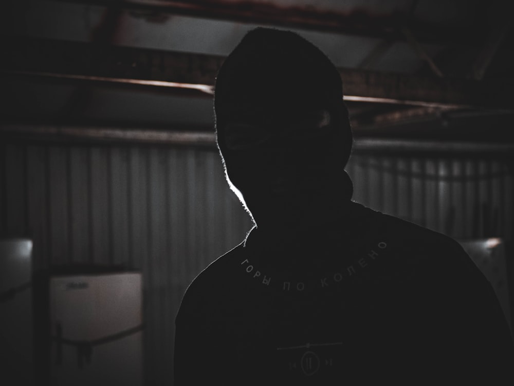 a person wearing a hoodie in a dark room