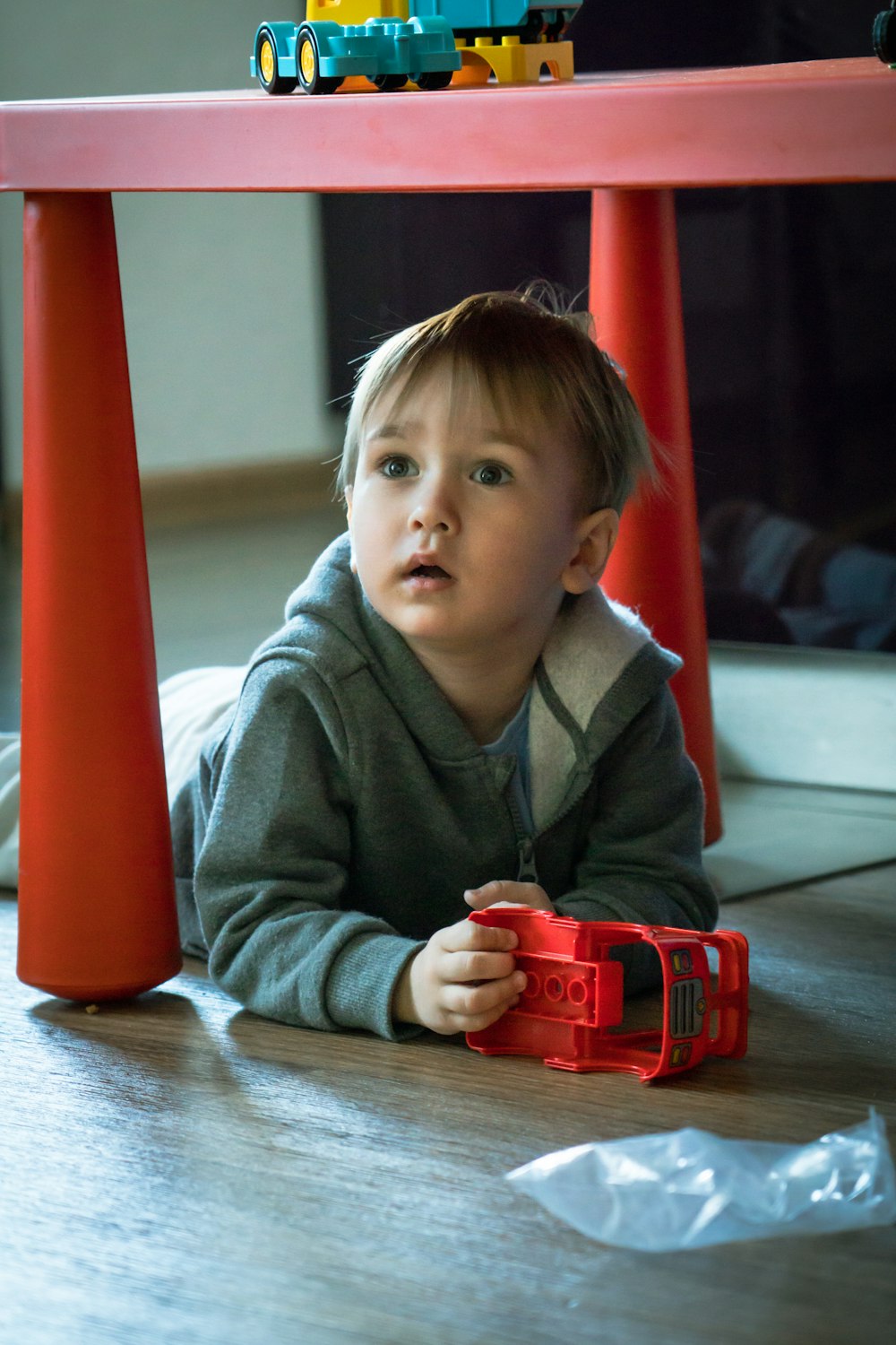 a little boy laying on the floor playing with a toy