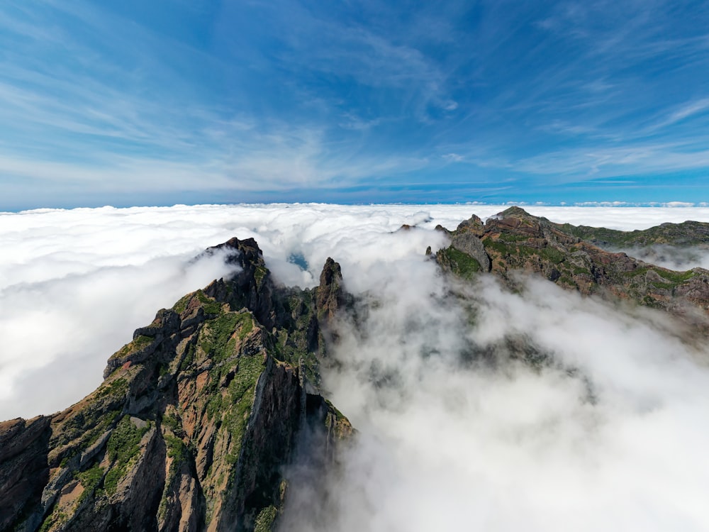 Une très haute montagne entourée de nuages sous un ciel bleu