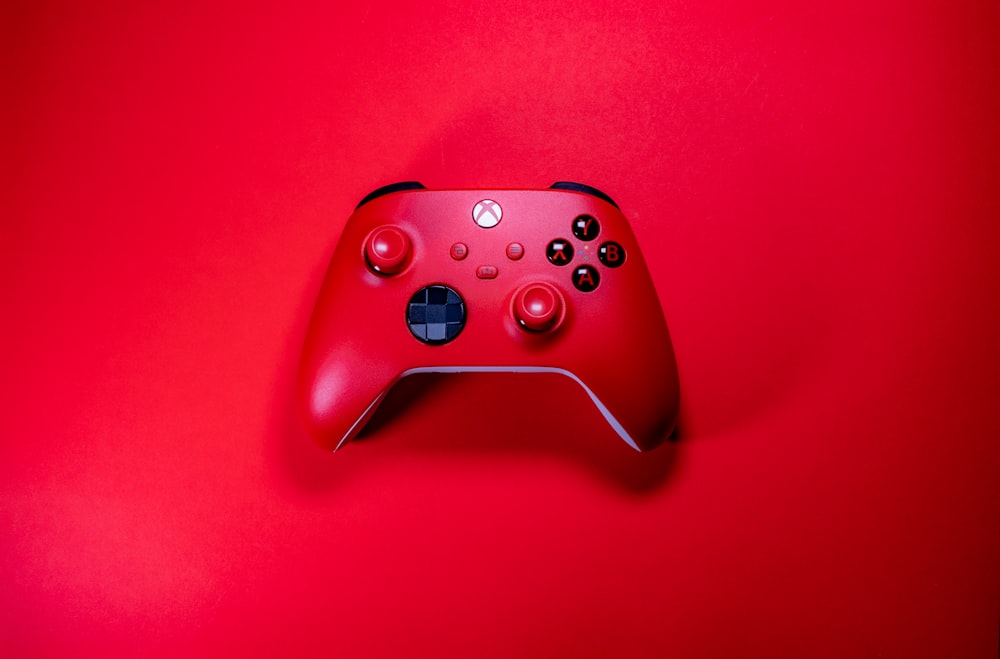 a close up of a red controller on a red surface