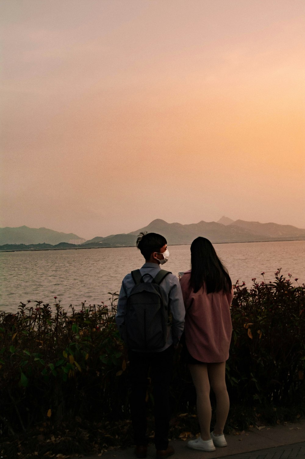 a couple of people standing next to a body of water