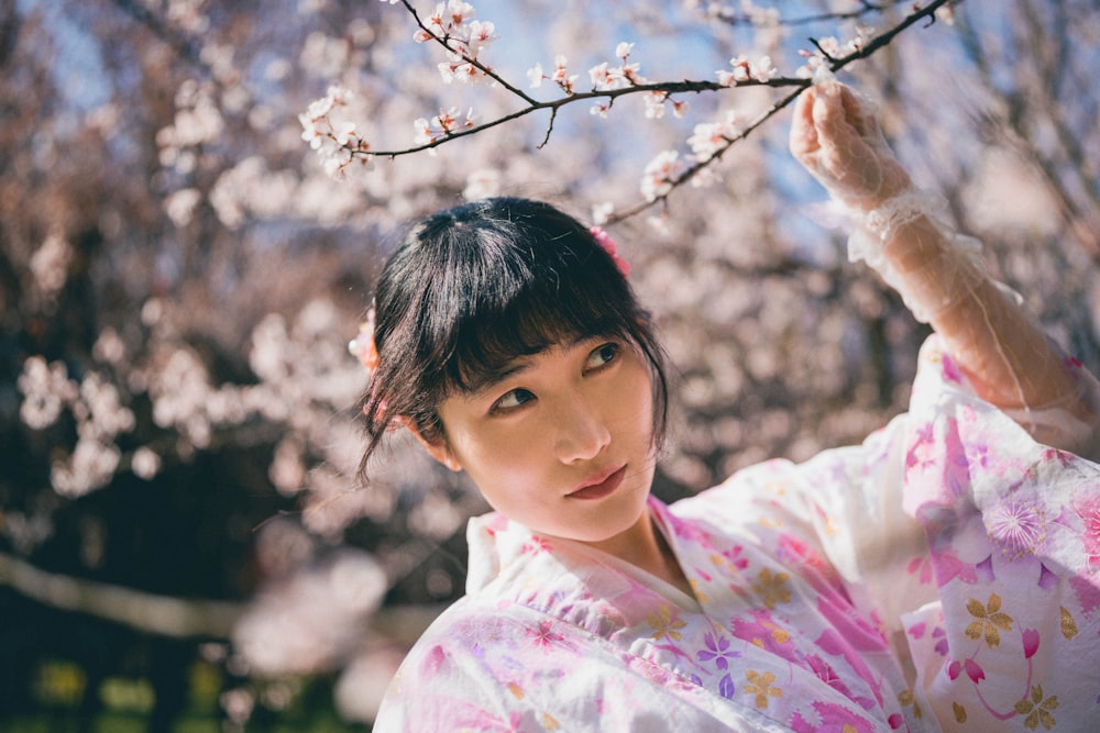 Eine Frau im Kimono steht unter einem Baum