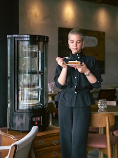 A happy woman enjoying a slice of gluten-free, sugar-free cake in a bright kitchen.