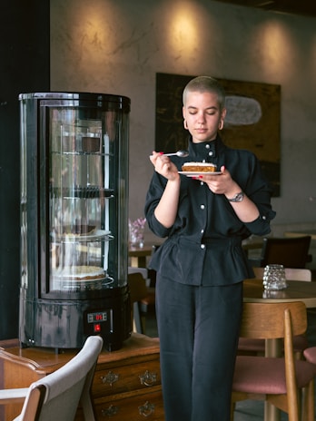A happy woman enjoying a slice of gluten-free, sugar-free cake in a bright kitchen.