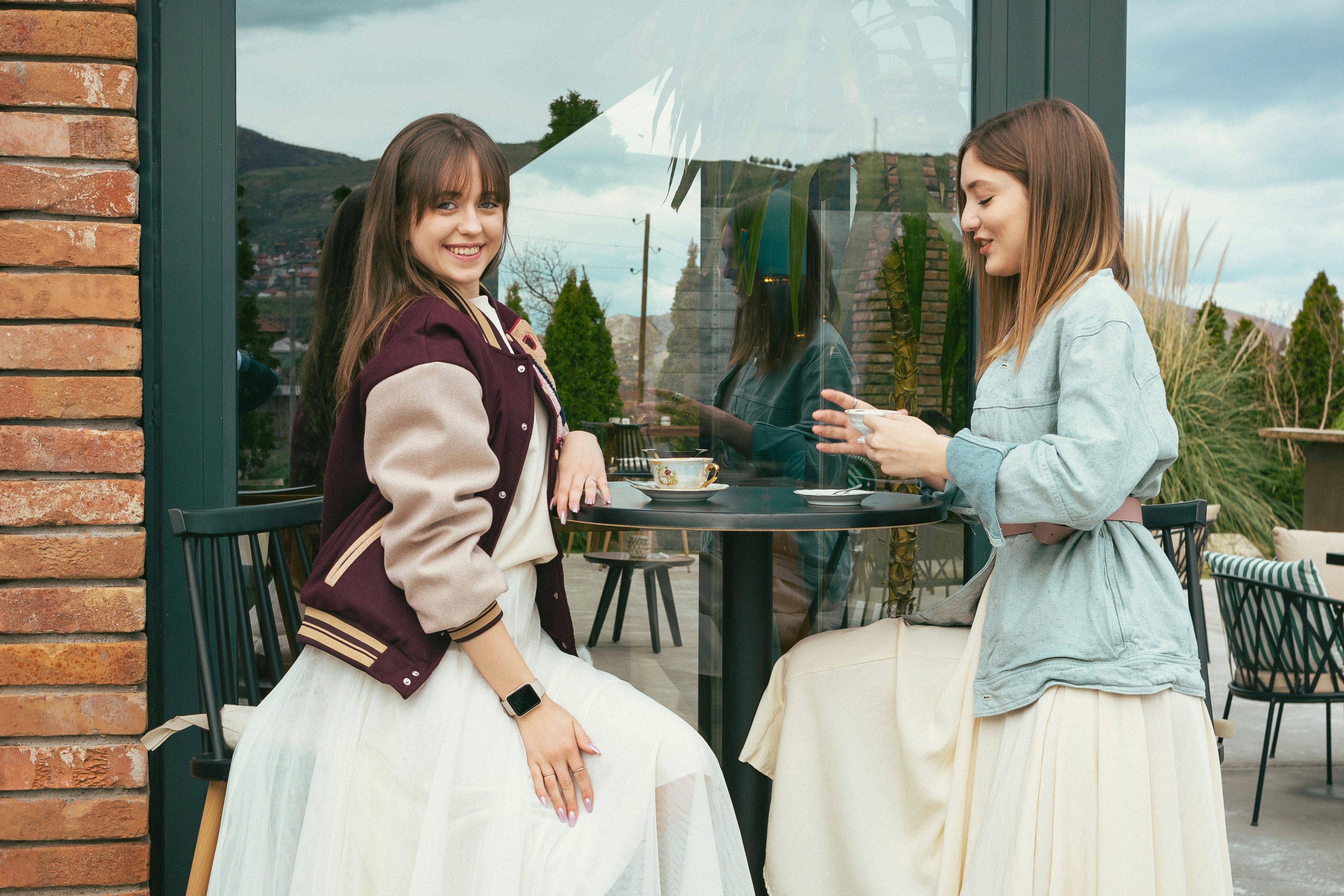 two women sitting at a table talking to each other, 