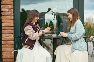 two women sitting at a table talking to each other