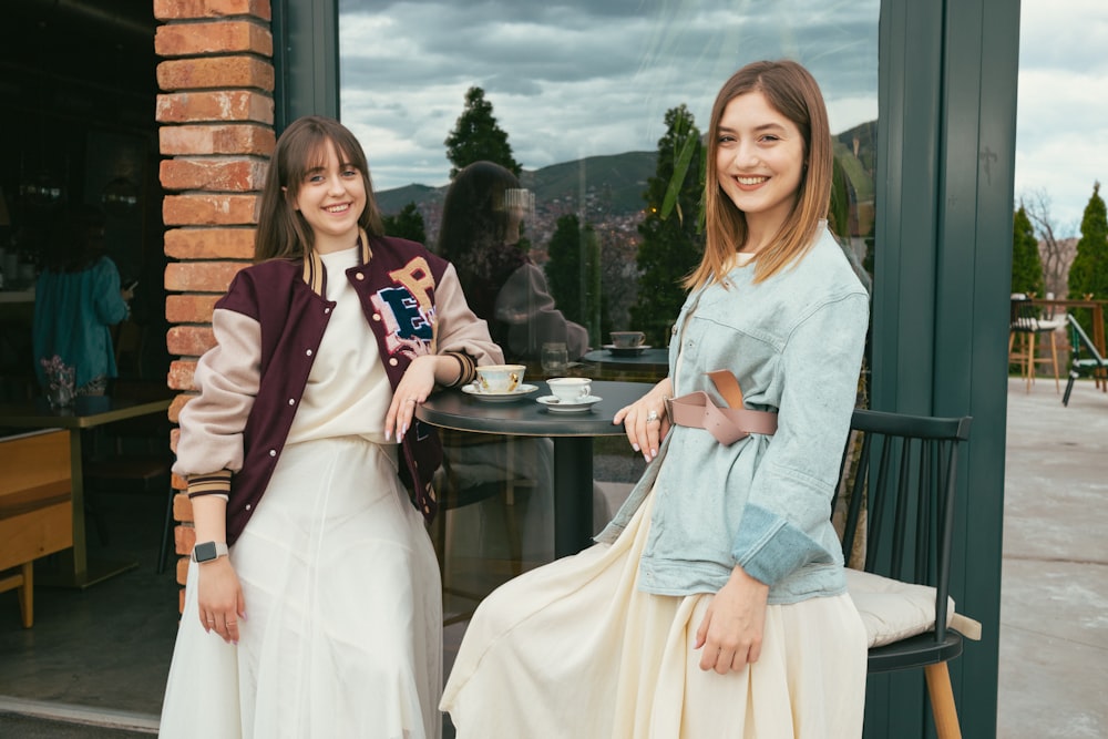 Dos mujeres sentadas en una mesa fuera de un café