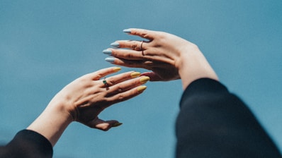 Bright, colorful gel nails catching the sunlight on an outdoor patio.