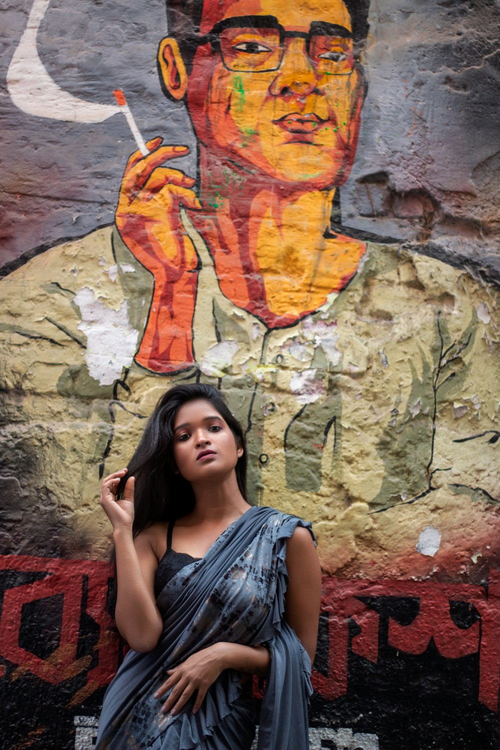 a woman standing in front of a painting of a man smoking a cigarette