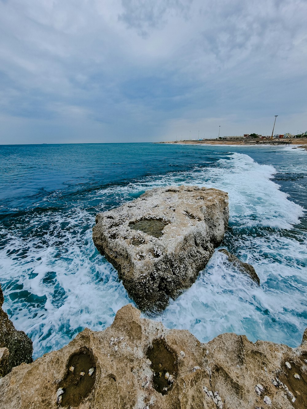 Una grande roccia seduta sulla cima di una spiaggia vicino all'oceano