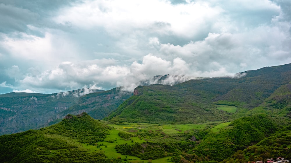 a lush green hillside covered in lots of clouds