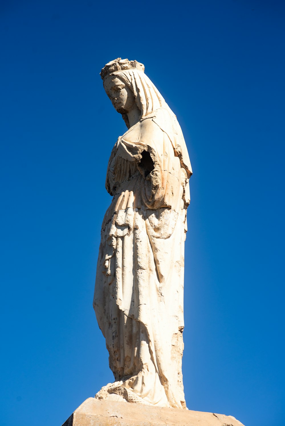a statue of a person holding a cross on top of a hill
