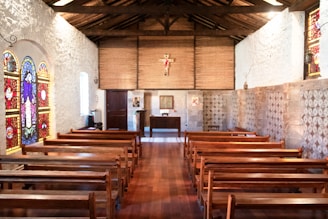 A peaceful chapel interior with wooden pews and stained glass windows.