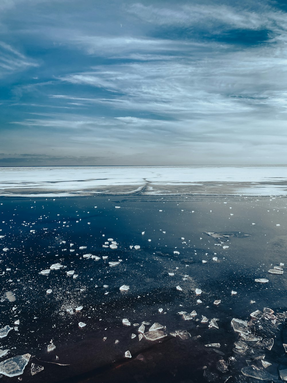 ice floes floating on the water under a cloudy sky