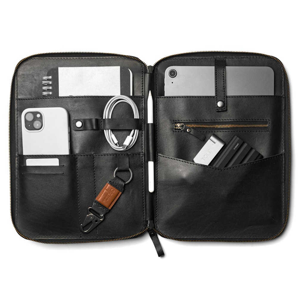 a black leather case with a key, wallet, and other items in it