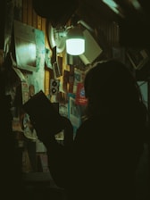A mysterious, shadowed figure reading a book in a cozy, dimly lit room.