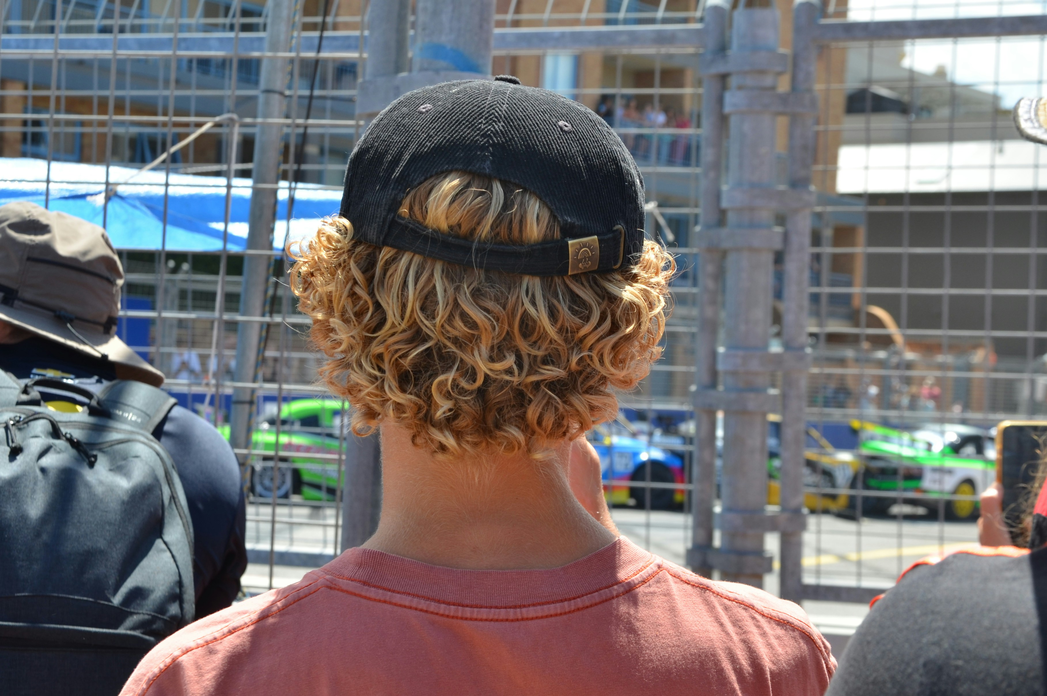 a man with curly hair wearing a black hat