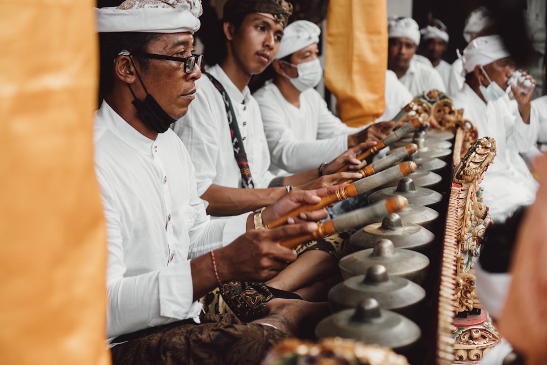 a group of people standing next to each other, Balinese people playing traditional music during religious ceremony in Ba