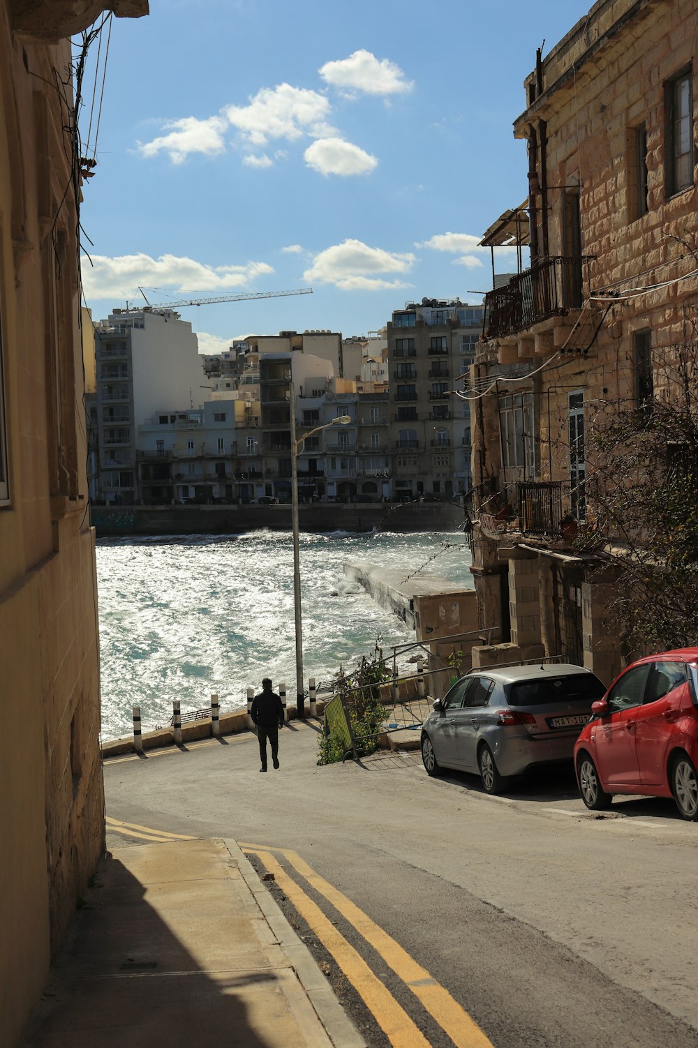 a man walking down a street next to a body of water