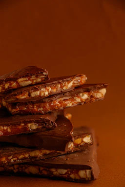 Delicious fitbar chocolate bars stacked with fresh ingredients like nuts and berries around them.