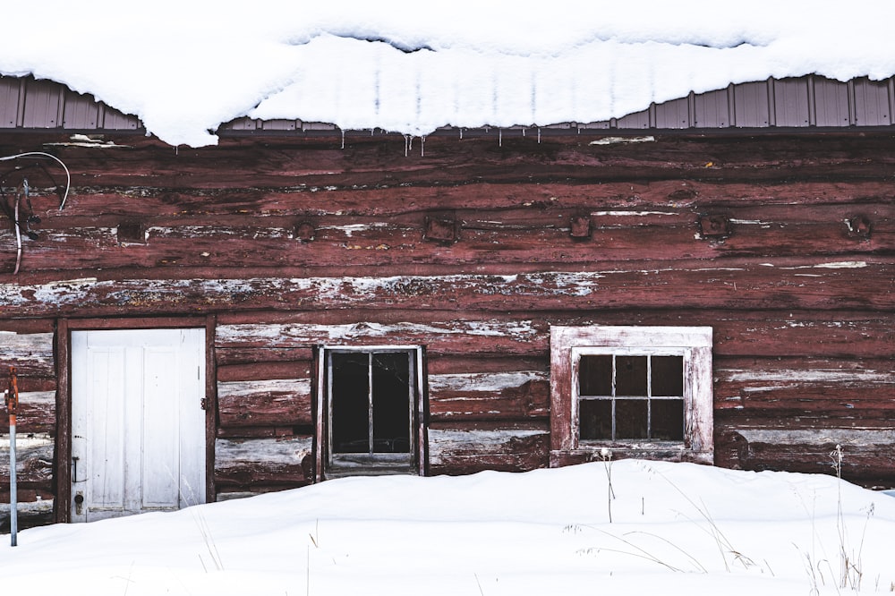 an old log cabin with snow on the roof