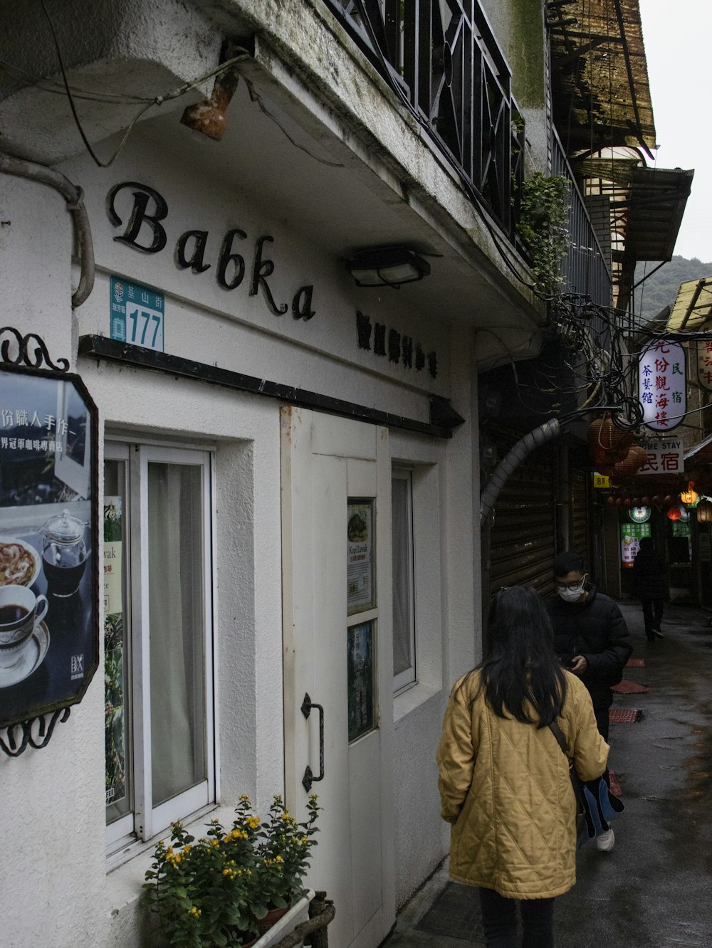 a woman walking down a street past a restaurant