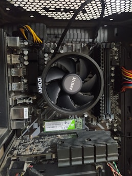 A computer motherboard with an AMD CPU cooler prominently displayed. The board includes various components such as RAM slots, power connectors, and a graphics card. The wiring is visible, with colored cables neatly arranged.