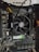 A computer motherboard with an AMD CPU cooler prominently displayed. The board includes various components such as RAM slots, power connectors, and a graphics card. The wiring is visible, with colored cables neatly arranged.
