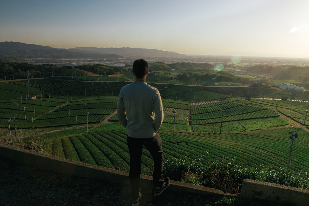 a man standing on top of a lush green hillside