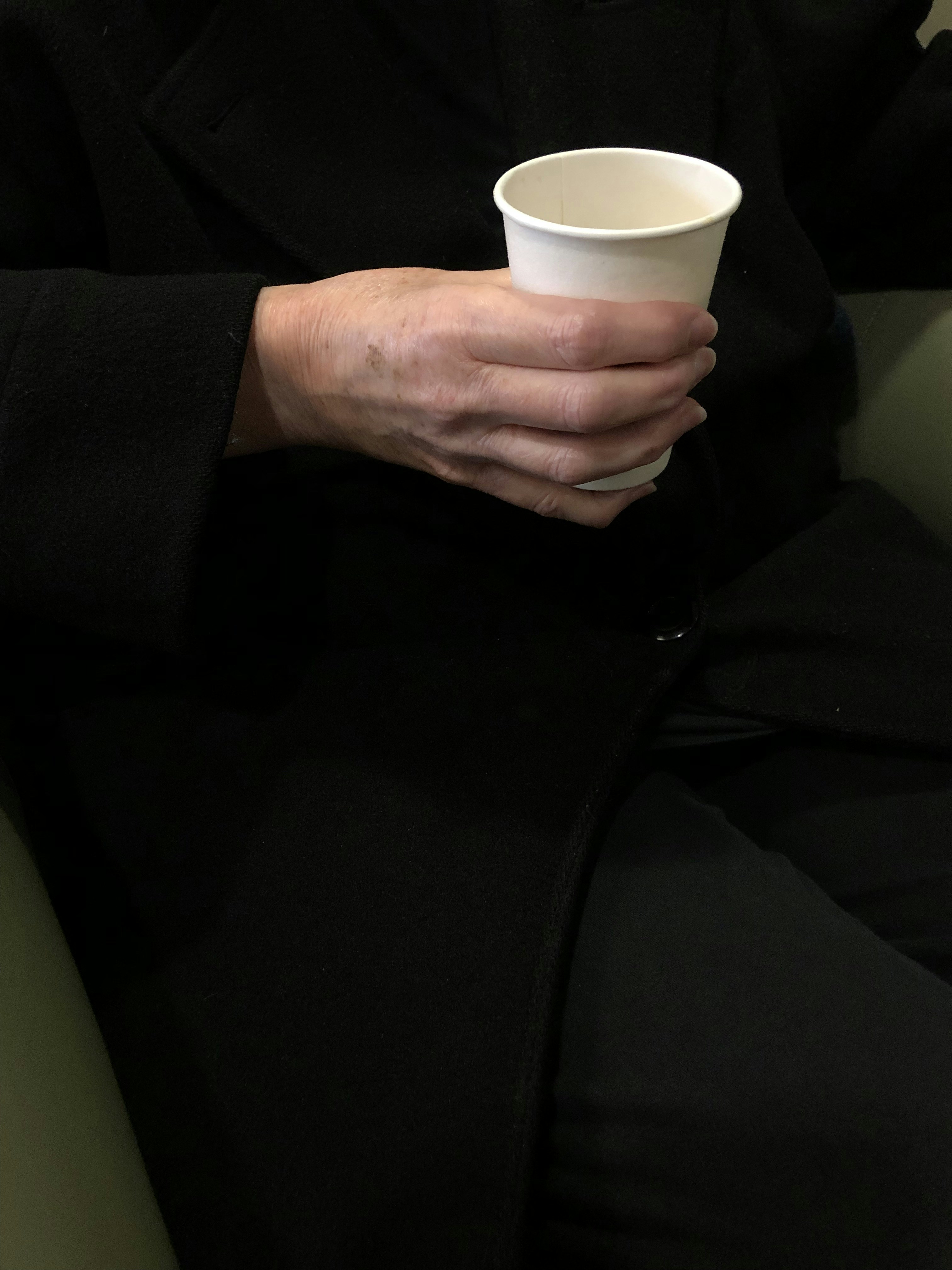 A person in a black coat holding a white cup photo – Free Coffee Image ...