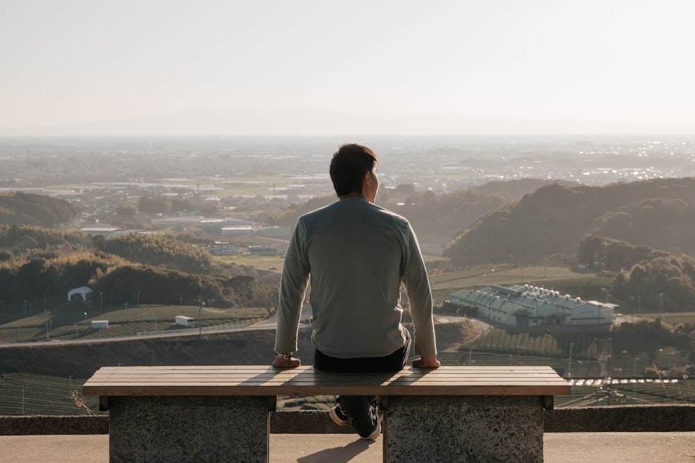 a man sitting on a bench looking out over a valley