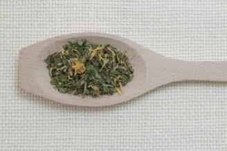 a wooden spoon filled with green tea on top of a table