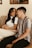 A couple sitting together on a couch, smiling and discussing their relationship.