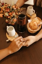 two people holding hands over a plate of food