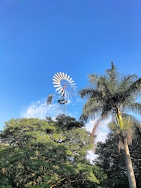 Windmill turbines turning gracefully against a clear blue sky in an industrial area.