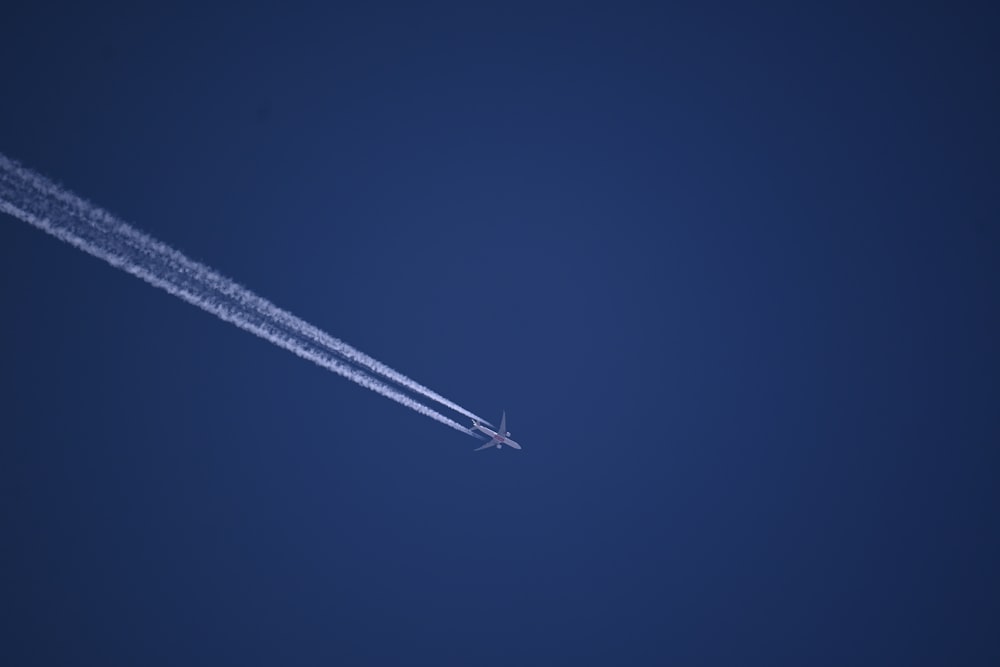 an airplane flying in the sky leaving a trail of smoke