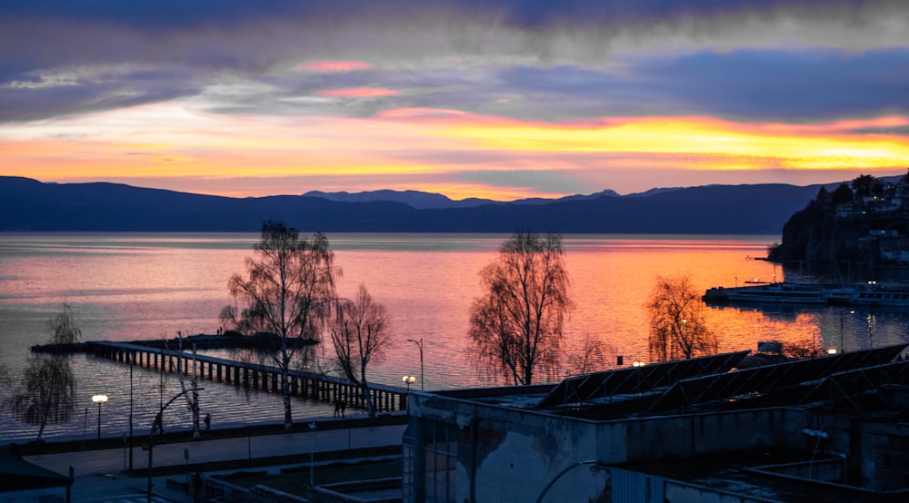 a sunset over a body of water with mountains in the background