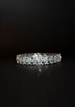 A beautifully crafted diamond bracelet lies against a dark background. The intricate design features multiple small diamonds arranged in a symmetrical pattern, enhancing its elegance and sparkle.