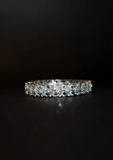 A beautifully crafted diamond bracelet lies against a dark background. The intricate design features multiple small diamonds arranged in a symmetrical pattern, enhancing its elegance and sparkle.