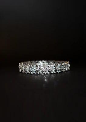 Men's diamond bracelet with a sleek design, photographed against a dark textured background.