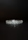 A beautifully crafted diamond bracelet lies against a dark background. The intricate design features multiple small diamonds arranged in a symmetrical pattern, enhancing its elegance and sparkle.
